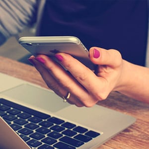 Person holding a phone with computer to contact Cabinet Joint