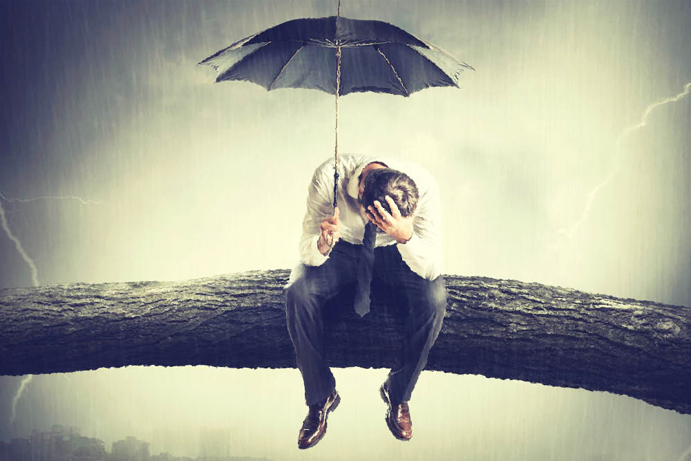 man holding umbrella seated on tree limb